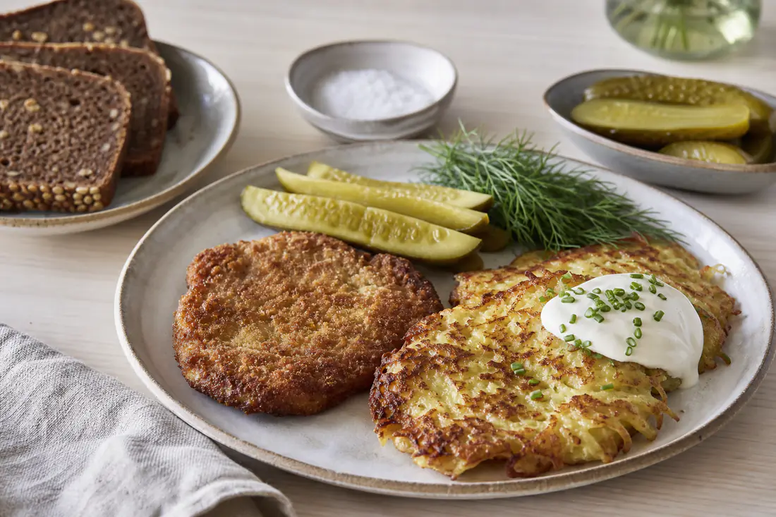 Kartoffelpandekager med creme fraiche, paneret svinekotelet, rugbrød og syltede agurker
