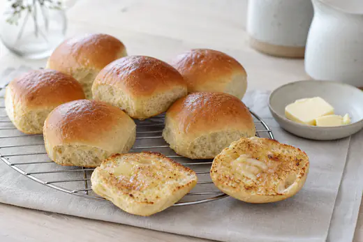 Gyldne firkantede hveder med blank top på en bagerist, to af dem flækket og ristet med smør