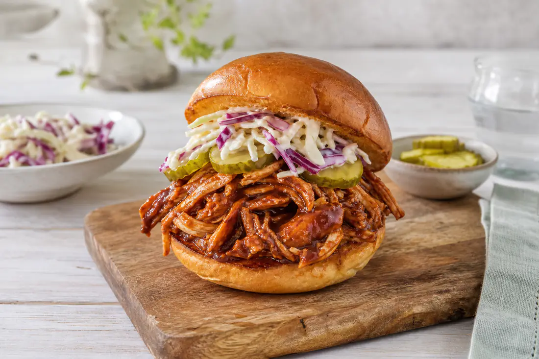 Trukket kylling i BBQ-sauce på en bolle med coleslaw og pickles