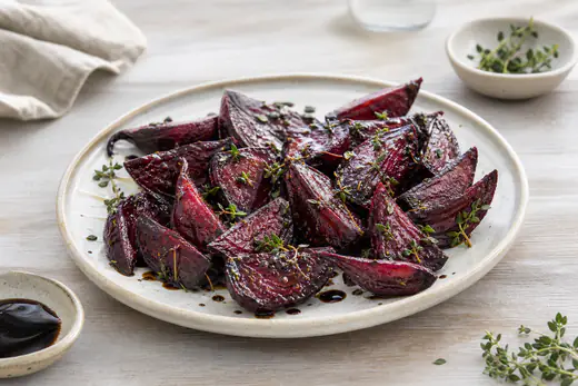 Bagte rødbedebåde med timian og dryp af balsamico på en lys tallerken